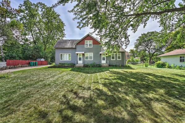 A two-story house with a front yard, a red fence, and a green lawn.