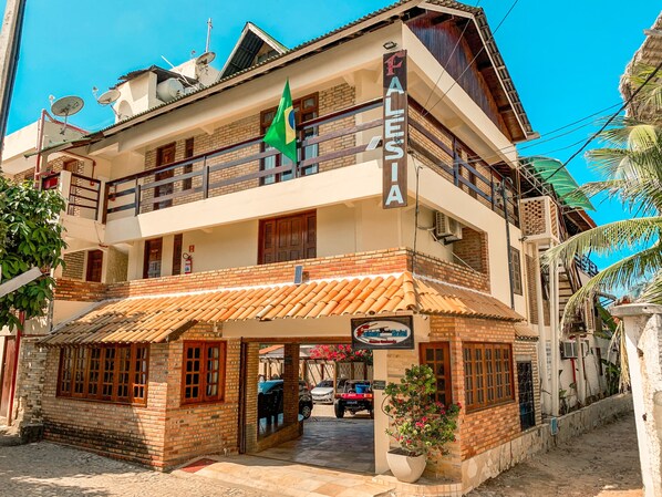 A two-story hotel with a balcony, a signboard, and a flag.
