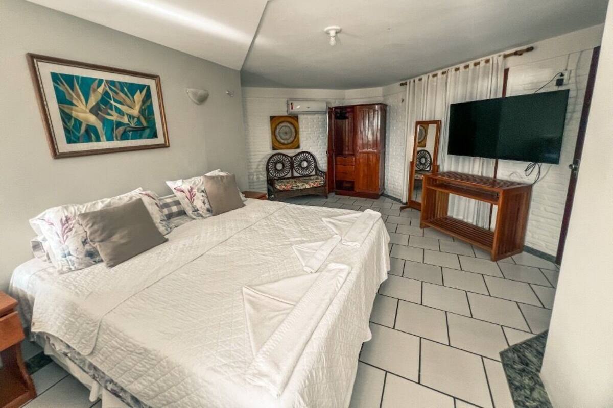 Une chambre à coucher avec un grand lit, une télévision et une porte donnant sur une autre pièce.