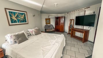 A bedroom with a large bed, a television, and a door leading to another room.