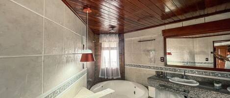 Ein Badezimmer mit Holzboden, einer Badewanne, einem Waschtisch und einem Spiegel.