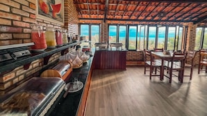 Ein Restaurant mit Backsteinwand, Holzboden und großen Fenstern mit Blick auf die Landschaft.