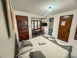 Habitación de hotel con cama, escritorio, silla, televisor y baño.