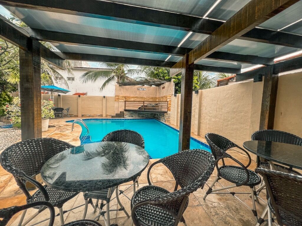 An outdoor pool area with a glass table and wicker chairs.