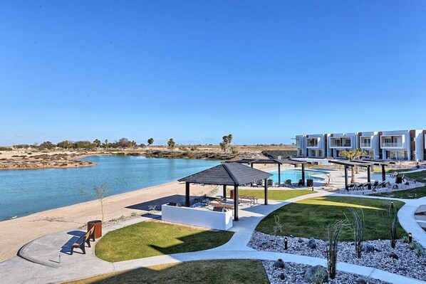 A modern resort with a pool, outdoor seating, and a view of the water.