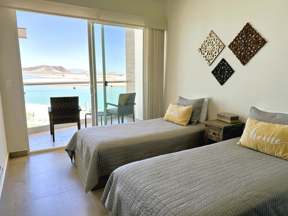 Une chambre d’hôtel avec deux lits, une vue sur la plage et un balcon.