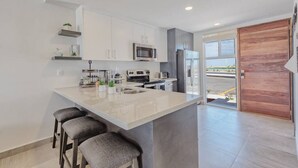 Une cuisine moderne dotée d’un îlot central, d’appareils électroménagers en acier inoxydable et de tabourets de bar.