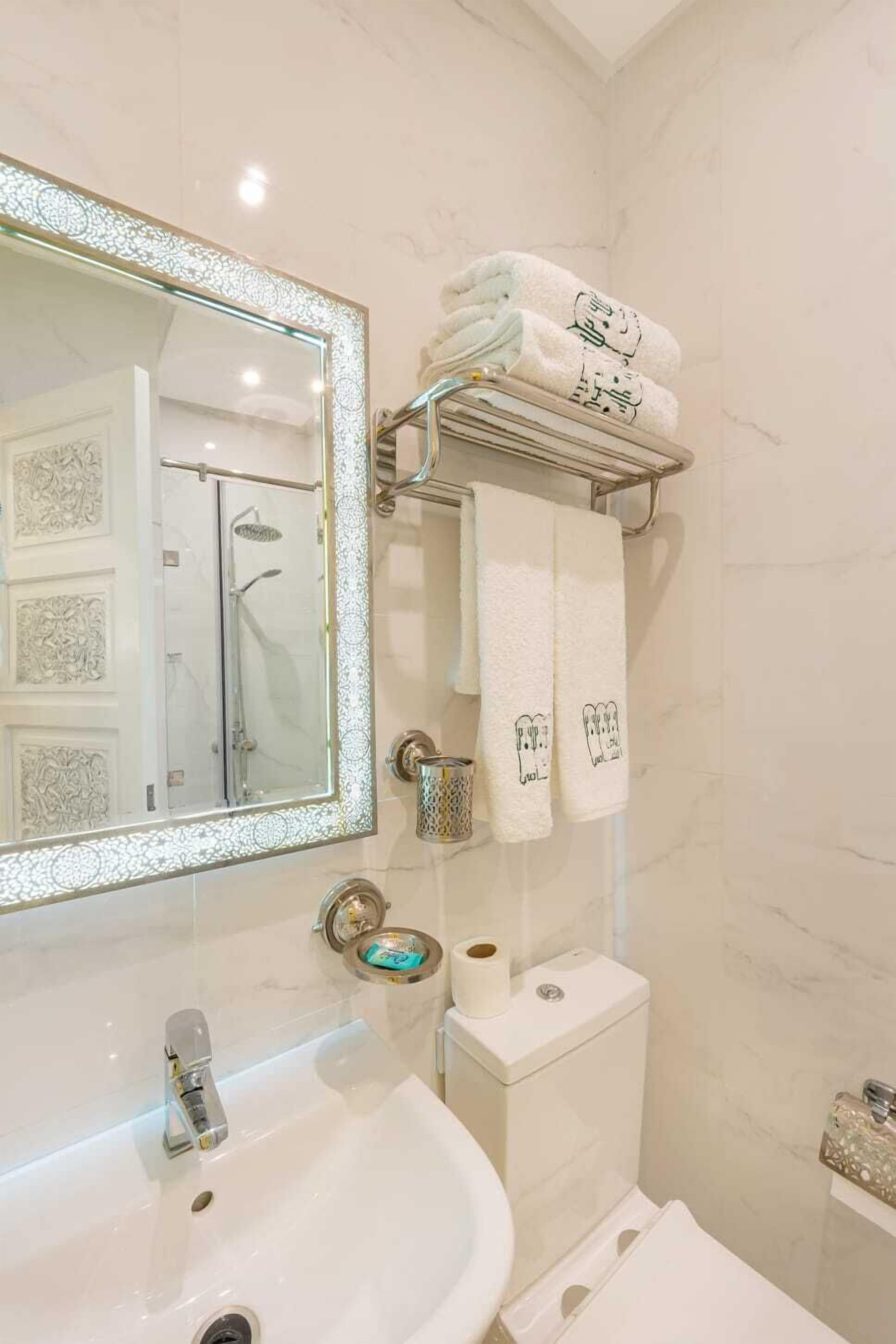 Une salle de bain avec un grand miroir, un lavabo, des toilettes et un porte-serviettes avec des serviettes.