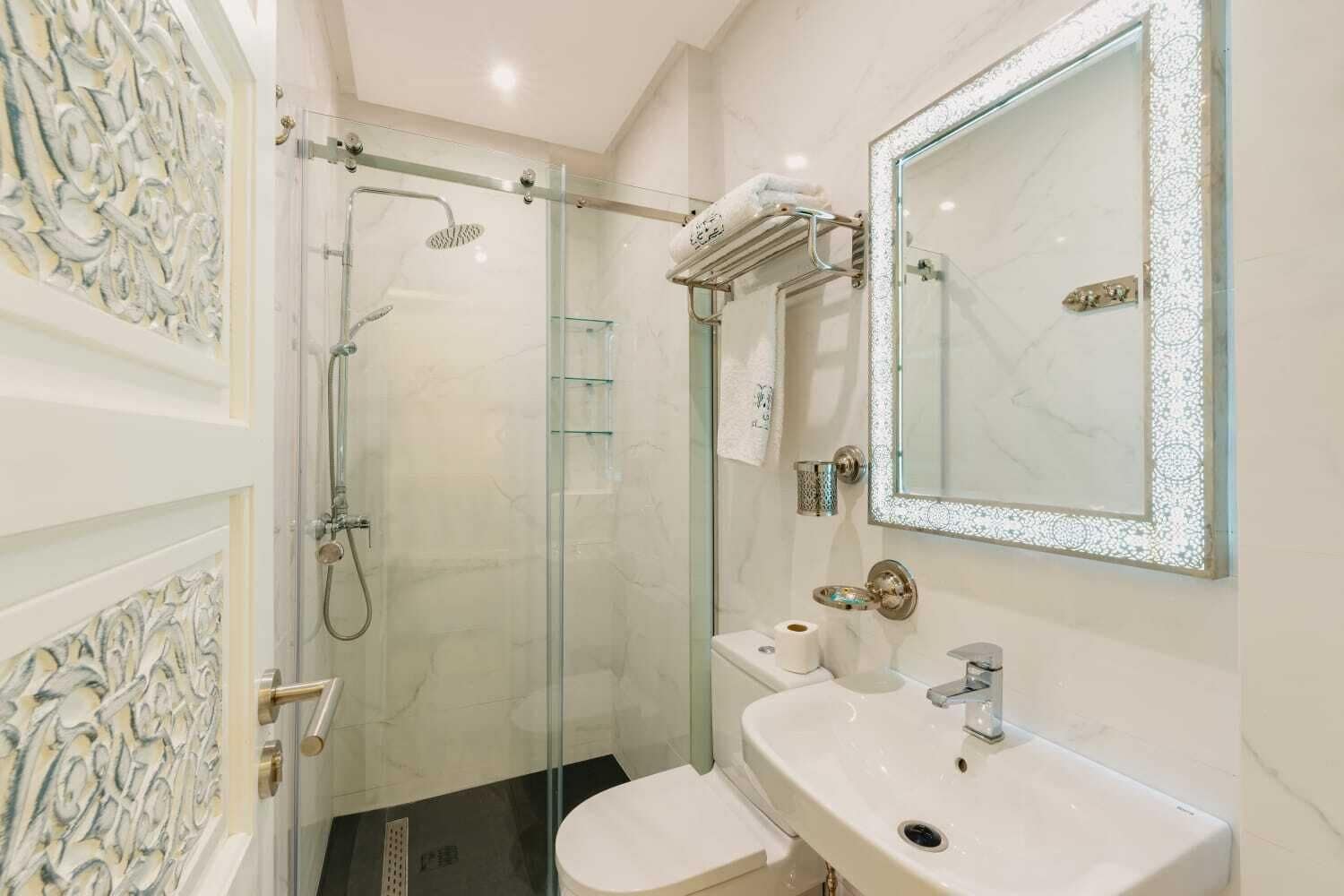 A modern bathroom with a glass-enclosed shower, a white sink, and a large mirror.