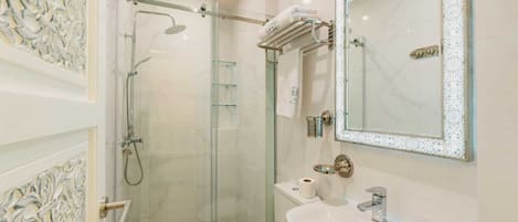 A modern bathroom with a glass-enclosed shower, a white sink, and a large mirror.
