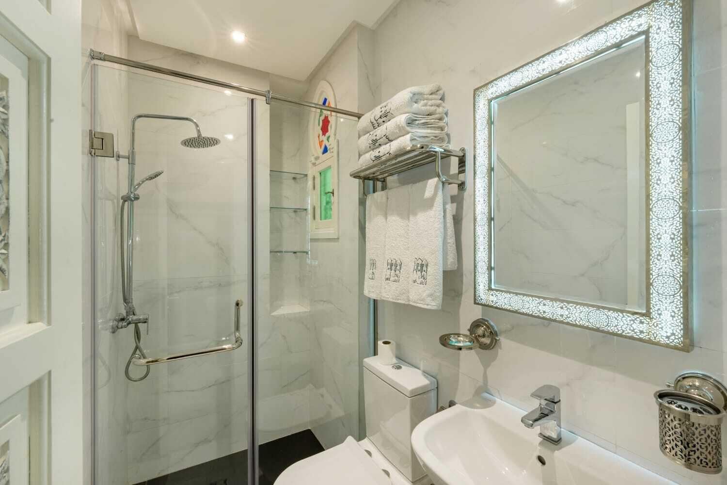 A modern bathroom with a glass-enclosed shower, a large mirror, and a white sink.