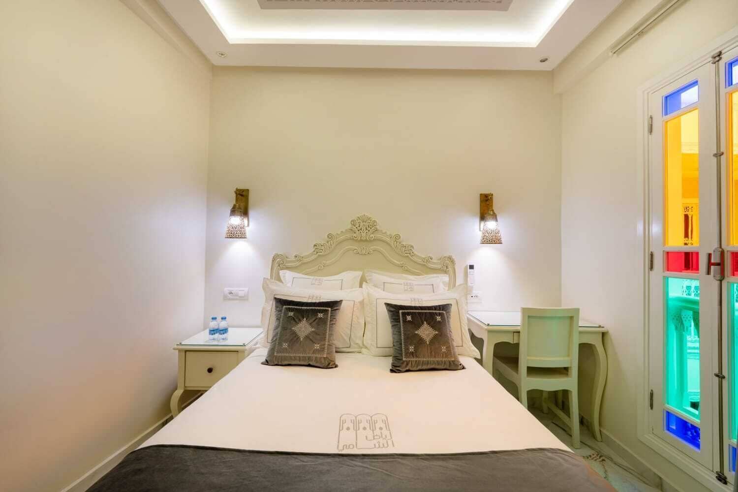 A hotel room with a large bed, two bedside tables, a desk, and a chair.