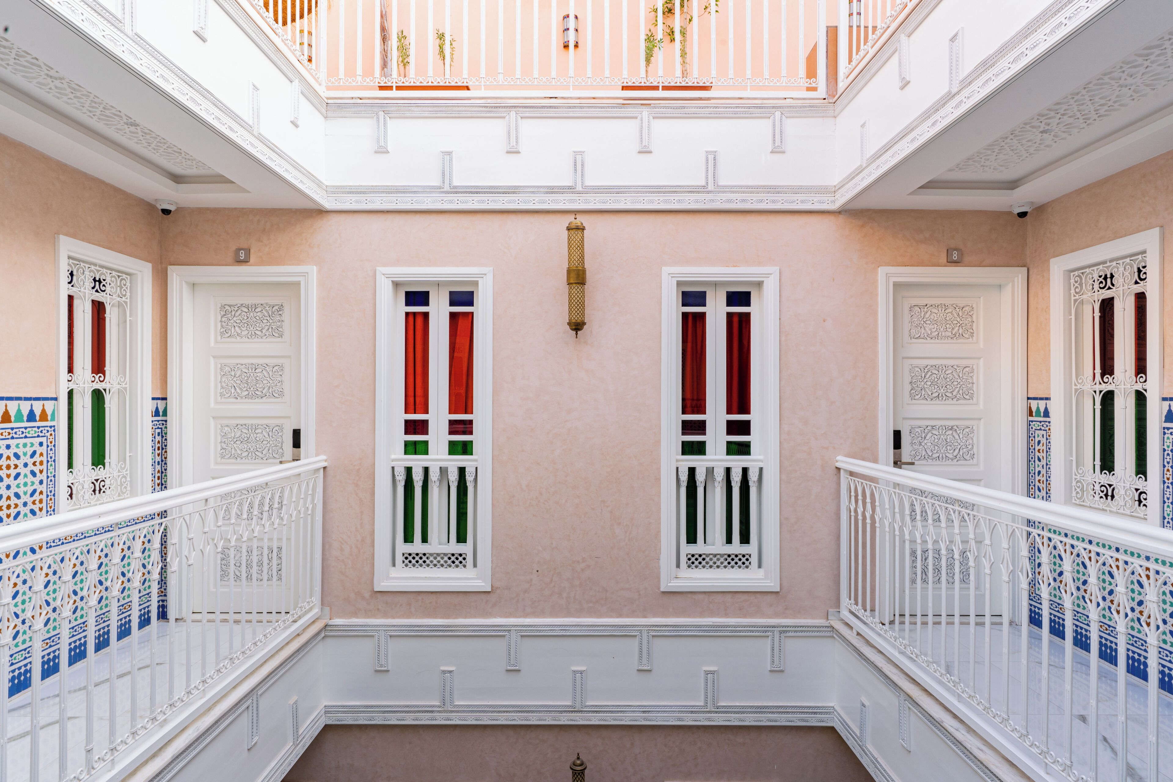 A multi-level interior with ornate white railings, decorative doors, and patterned windows.