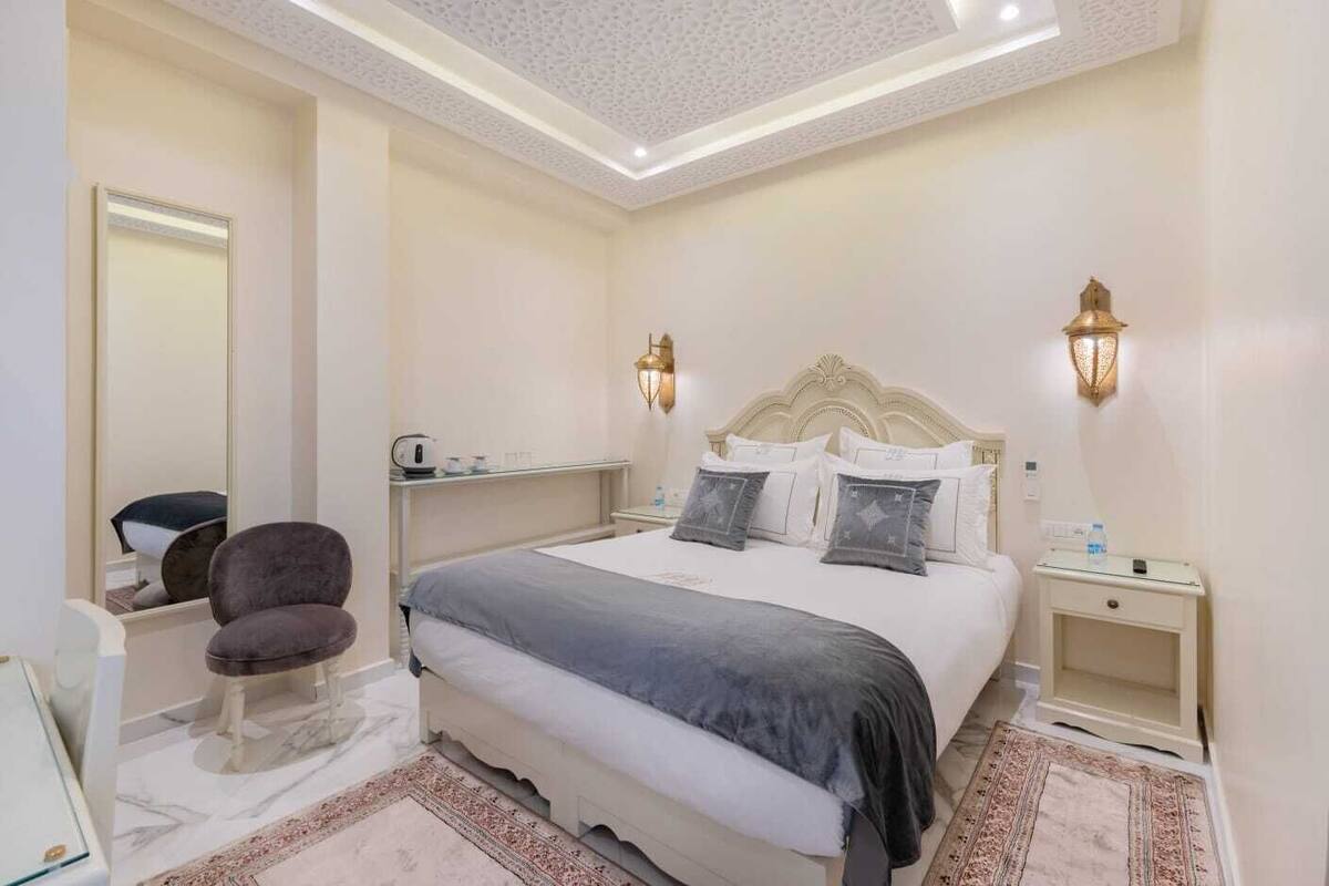 A modern bedroom with a large bed, bedside tables, a chair, and a mirror.