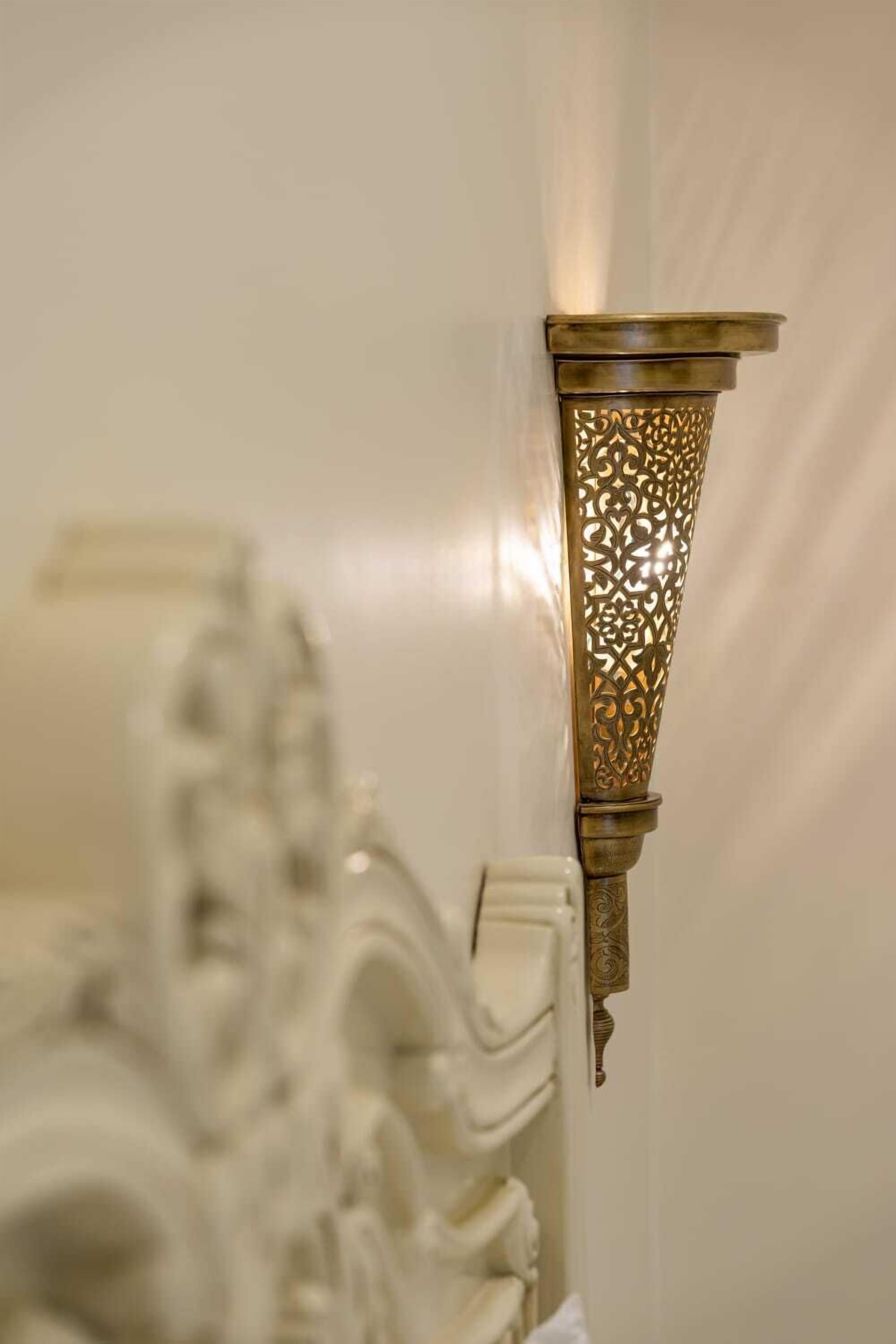 Eine Wandleuchte mit aufwendigen Mustern und metallischer Oberfläche.