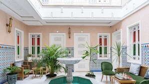 A luxurious interior with a central fountain, ornate doors, and a seating area with green upholstered chairs. - Hotel Riad Chami (Marrakech)