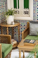 Una habitación con un sofá verde, una mesita redonda con una planta y una estantería.