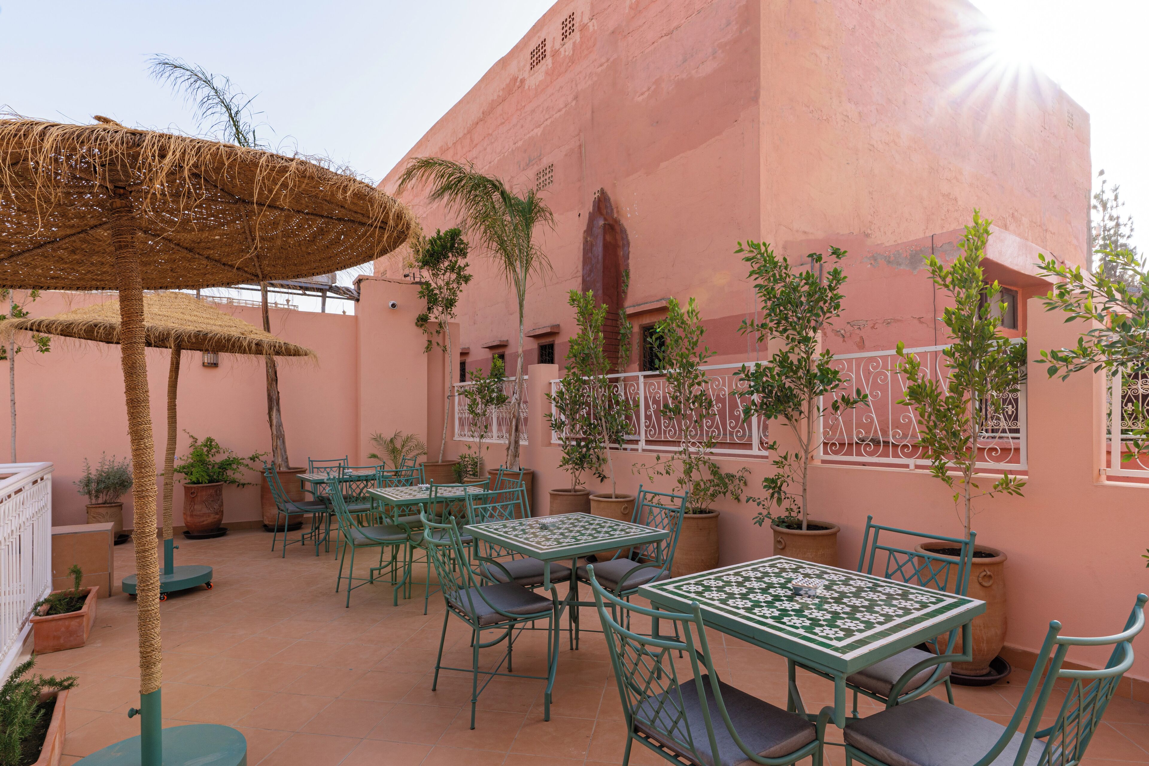 An outdoor patio with tables and chairs, surrounded by potted plants and a decorative umbrella.