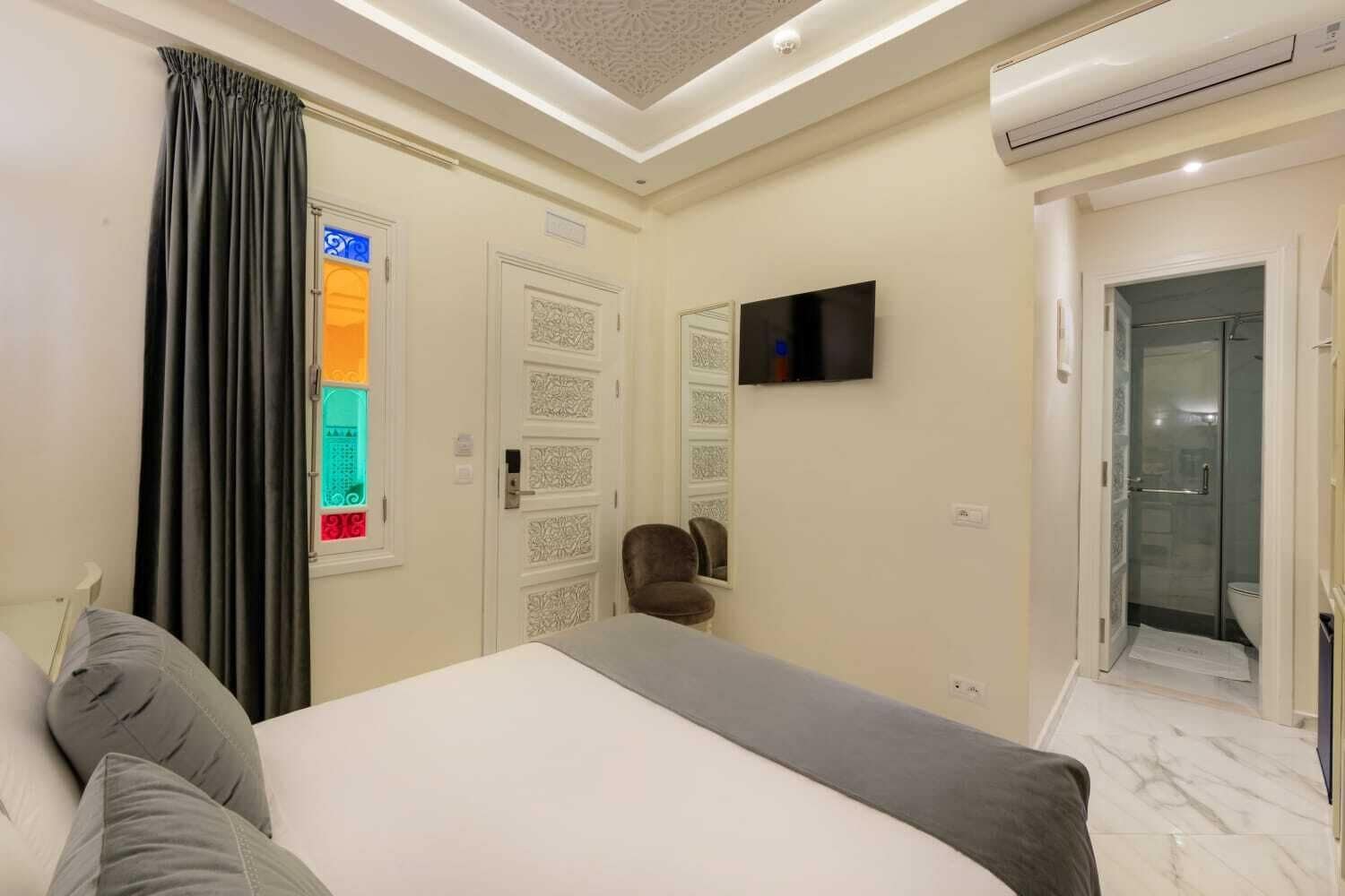 Een hotelkamer met een bed, een televisie, een douche en een deur met een ruit.