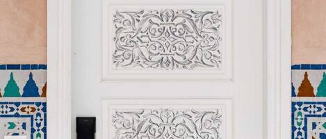 A white door with intricate carvings and a numbered plaque above it.
