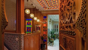 An ornate hallway with intricate woodwork, a patterned carpet, and a stained glass ceiling. - Hotel Riad Chami (Marrakech)