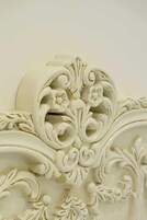 A close-up of ornate white wall molding with floral and scroll designs.