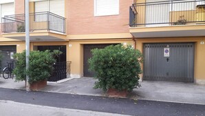 A two-story building with a yellow facade, a black metal balcony, and a closed garage door. - Panoramic penthouse a few meters from the sea and the promenade of Terracina (Terracina)