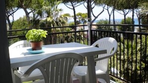 A balcony with a white table and chairs, a potted plant, and a view of trees and the sea. - Panoramic penthouse a few meters from the sea and the promenade of Terracina (Terracina)