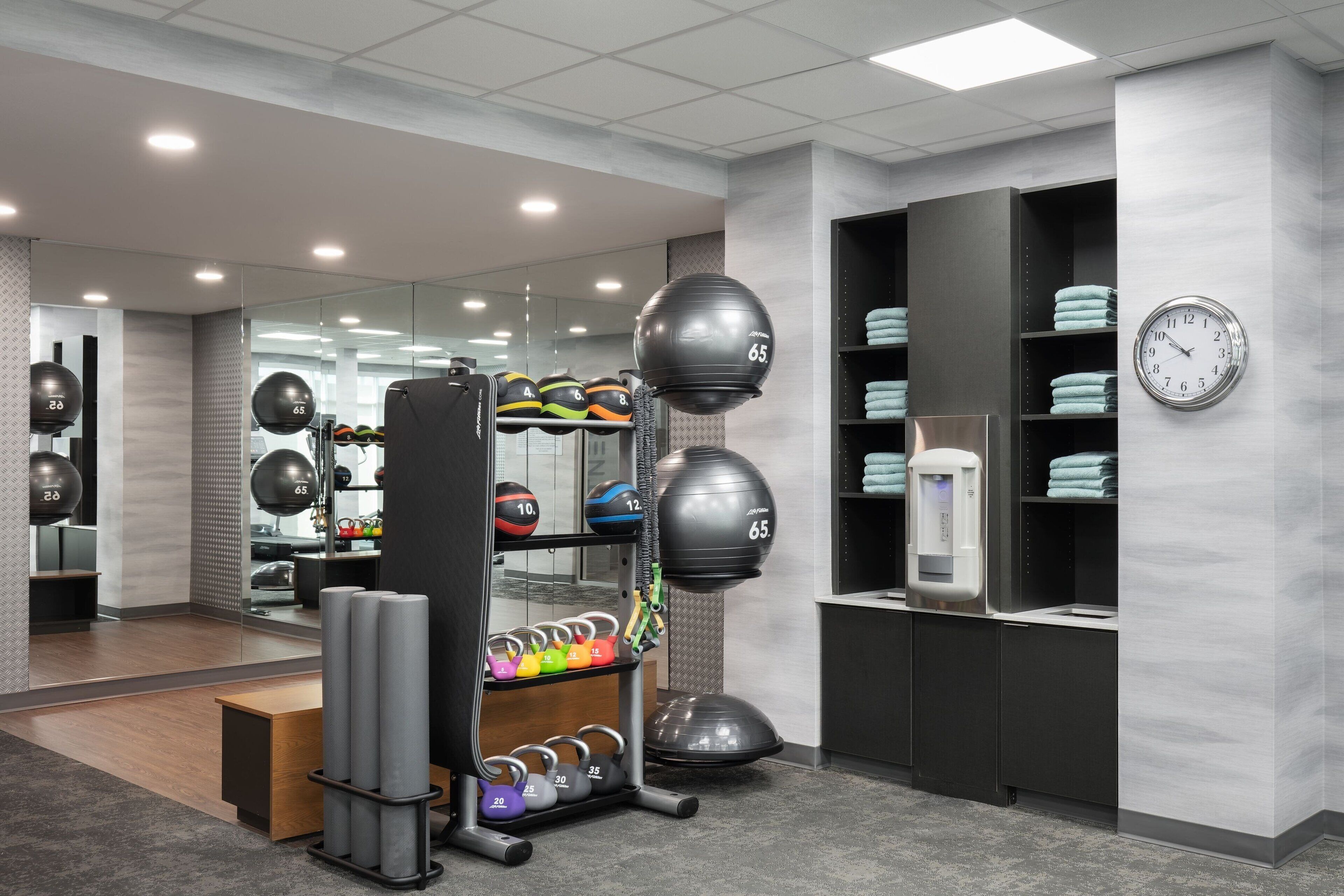 Un gimnasio moderno con diversos equipos de ejercicio, incluyendo kettelbells, balones medicinales y un saco de boxeo.