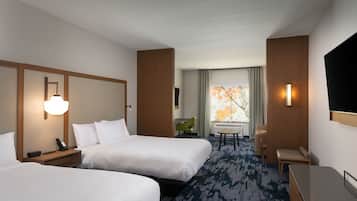 Une chambre d’hôtel avec deux lits, un bureau, une chaise, une télévision et une fenêtre donnant sur un beau paysage.