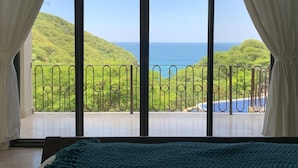 A room with a large window overlooking a lush green landscape and a clear view of the ocean.