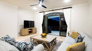 A living room with a TV, sofa, coffee table, and a balcony with a view.