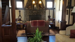 A traditional living room with a stone fireplace, wooden furniture, and a clock on the wall. - Catskill Classic Charm (Saugerties)