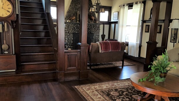 A wooden staircase, a fireplace with stone accents, a cozy armchair, and a round table with a plant. - Catskill Classic Charm (Saugerties)