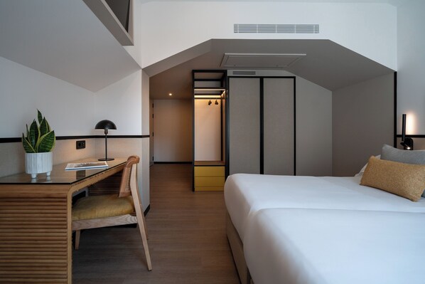 Quarto de hotel com escrivaninha, cadeira, cama e closet espaçoso.