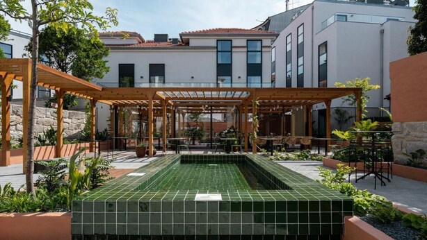Un patio con piscina de baldosas, pérgolas de madera y mobiliario exterior.