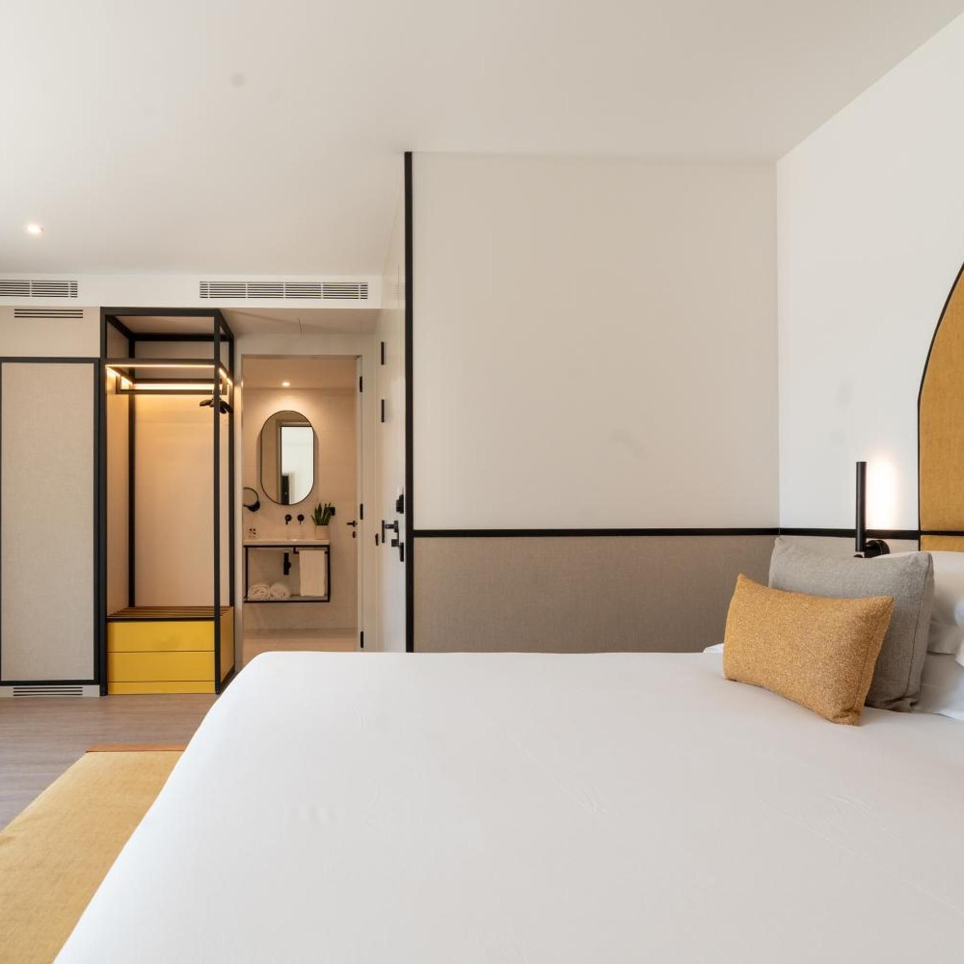 Un dormitorio moderno con una cama grande, una mesita de noche, un espejo y un armario.