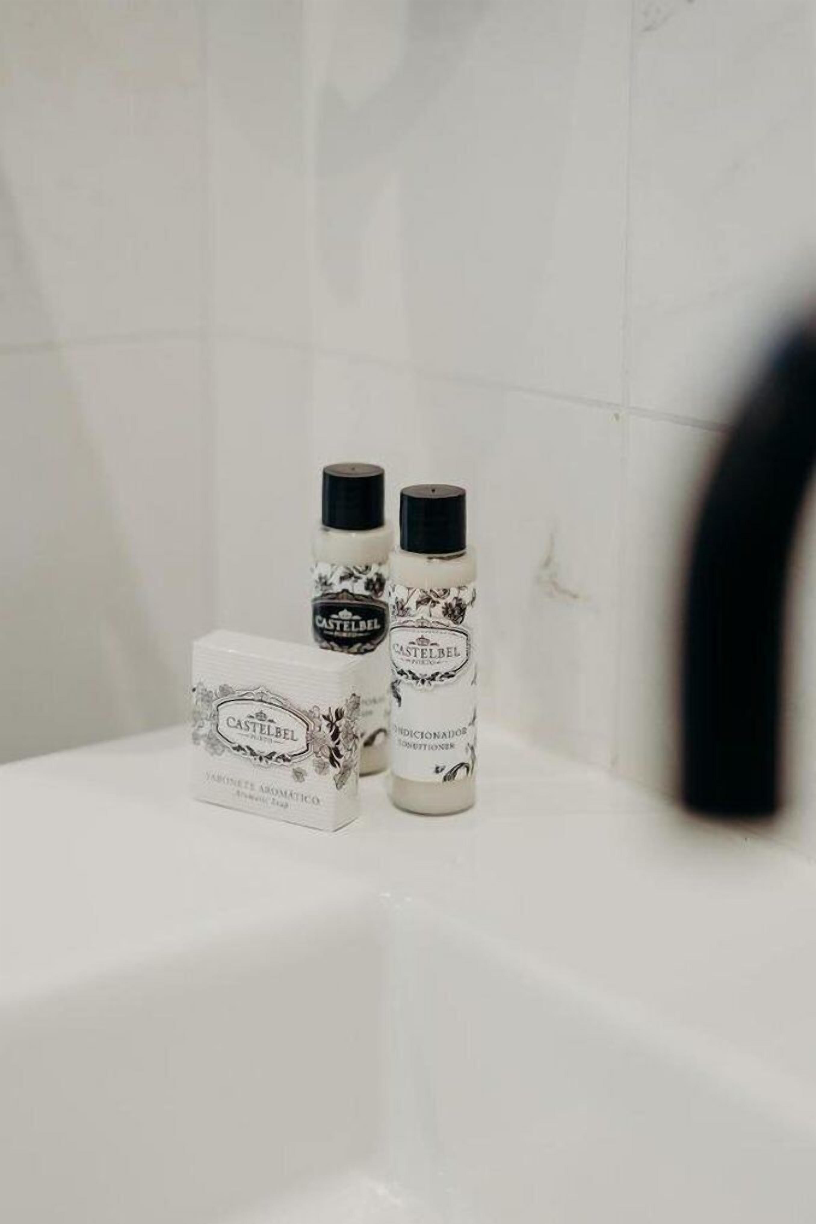Ein Badezimmer mit einer weißen Badewanne, zwei Flaschen Castelbel Duschgel und einem Castelbel Seifenstück.