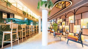 Un interior moderno con una zona de bar, asientos y plantas decorativas.