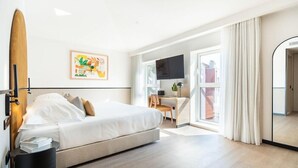 Una habitación de hotel con cama, escritorio, televisor y un espejo grande.