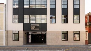 Un edificio moderno con un letrero que dice 'The Editory Garden Hotel'. Presenta una fachada plana con ventanas grandes y una entrada negra.