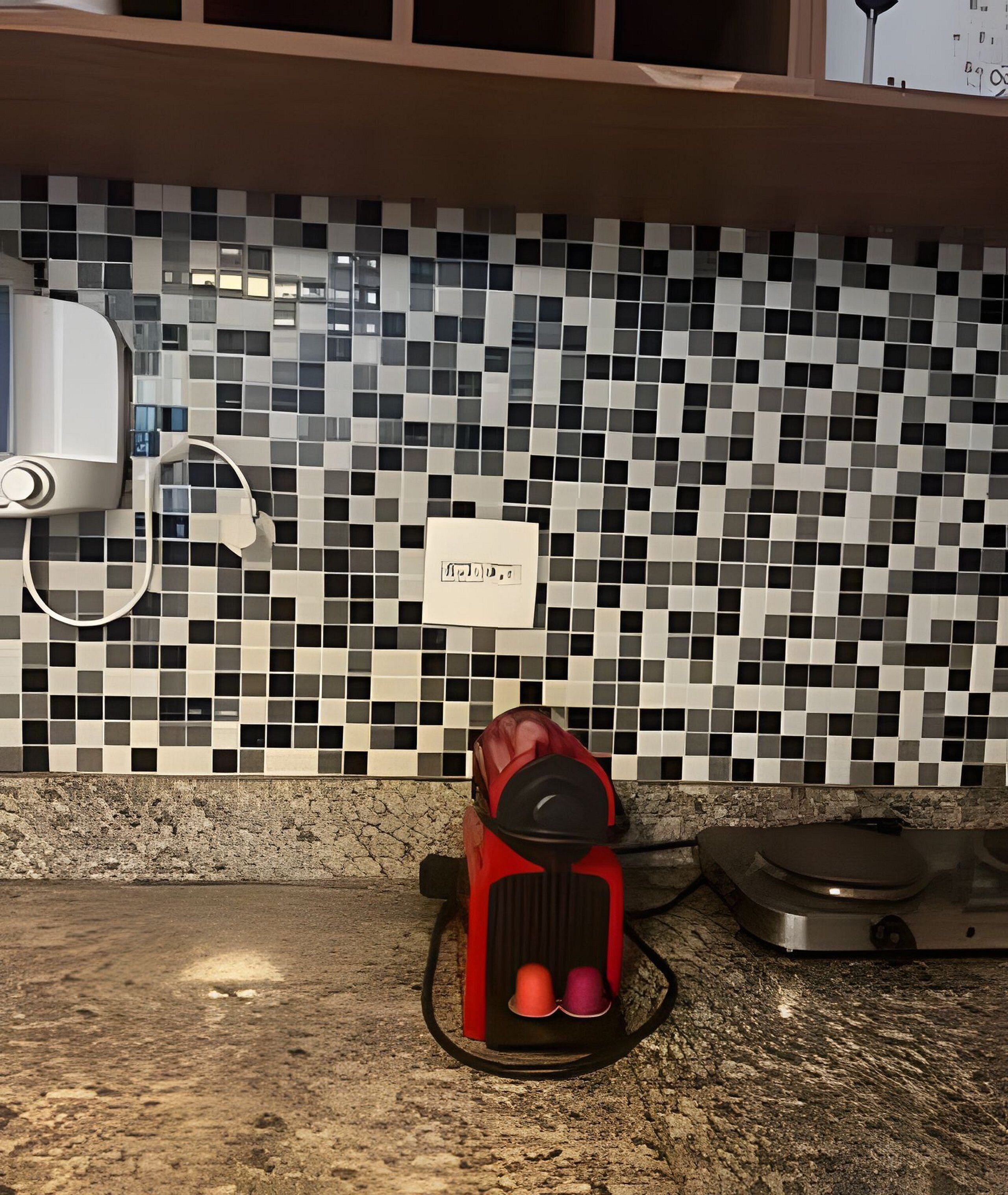 A kitchen with a tiled backsplash, a coffee maker, and a scale on the counter.