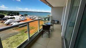 A balcony with a view of boats on a beach and a body of water. - Brisas do Lago - Apartamento 4 (Brasília)