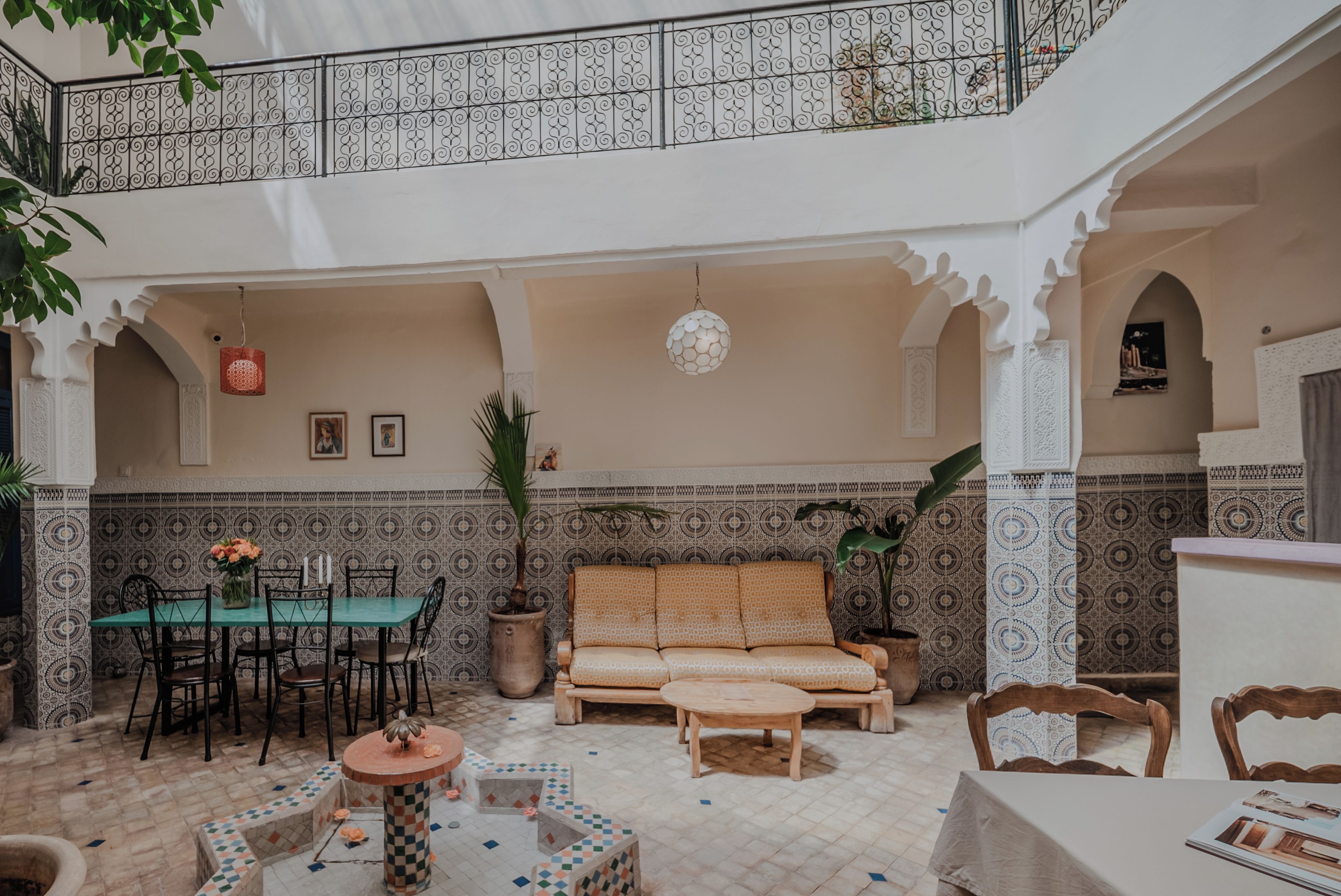 Un intérieur spacieux avec un plafond haut, un coin repas, un espace salon avec un canapé et un pouf, et un plafond décoratif agrémenté d’un luminaire suspendu.