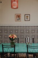 Un comedor con una mesa, sillas, un jarrón con flores y dos cuadros en la pared.