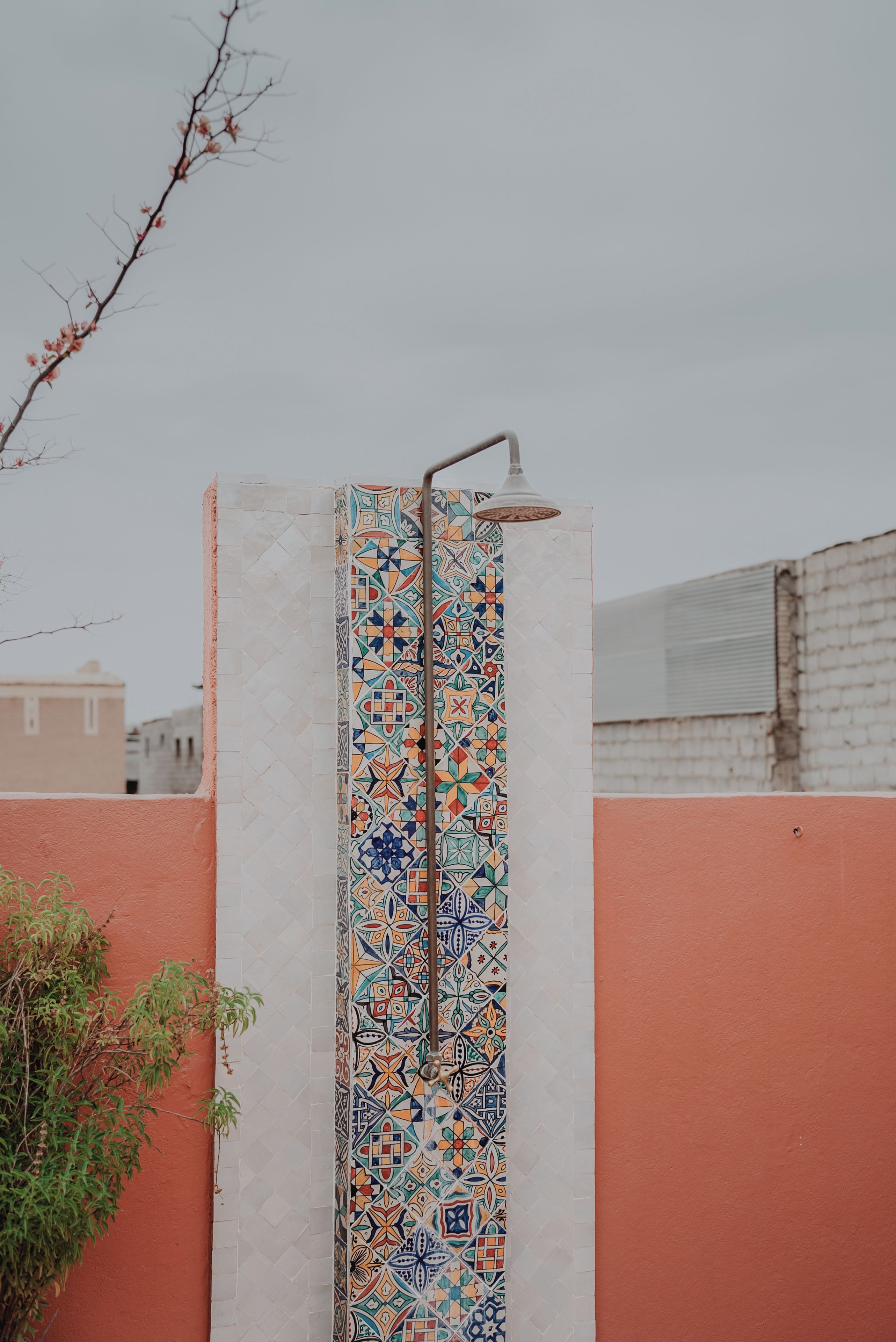 A vertical wall with colorful geometric tile patterns and a metal showerhead.