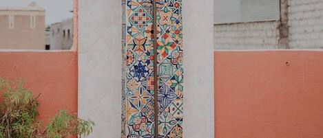 A vertical wall with colorful geometric tile patterns and a metal showerhead.