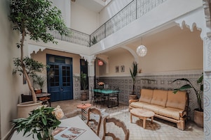 Un patio amplio con zona de comedor, un sofá y una escalera que lleva a un nivel superior.