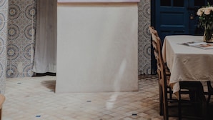 A restaurant with a white table, a blue door, and a menu board. - Riad Imndi (Marrakech)