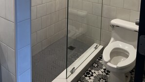 A modern bathroom with a glass-enclosed shower, a toilet, and a tiled floor. - Cindy Lyn Motel (Cicero)